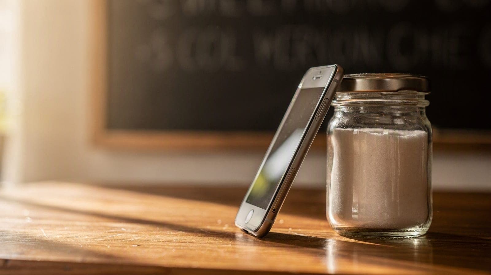 A café counter with a phone propped against a sugar jar